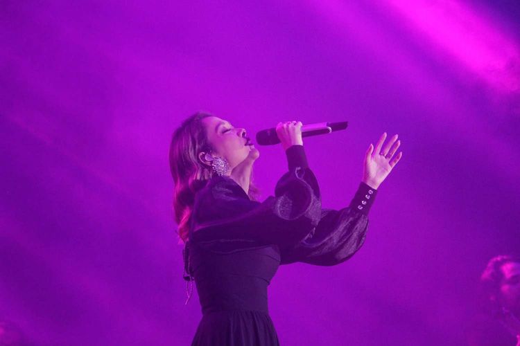 Bunga Citra Lestari atau BCL mengenakan gaun hitam sambil menyanyi di atas panggung